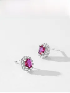 Macro view of luxury 925 silver halo stud earrings with oval red zircon and pavé diamonds