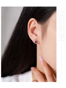 Close-up of 925 sterling silver red zircon oval stud earrings on model's ear