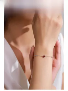 Detailed view of a silver 925 bracelet with a red square gemstone on a woman's wrist