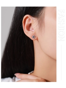 Close-up of blue four-leaf clover stud earring with sparkling cubic zirconia on model