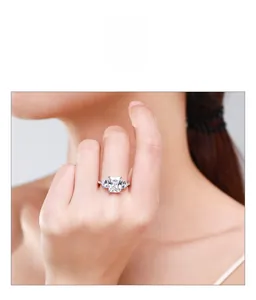 Détail d'une bague taille émeraude de 3 carats avec pierres en poire sur le doigt