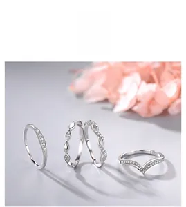 Detail view of four silver 925 rings with white zircon stones on a grey surface