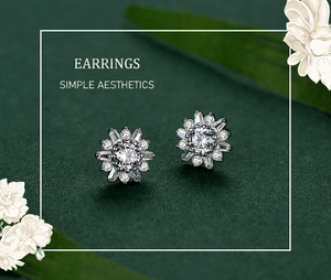 Détail des boucles d'oreilles tournesol en argent avec zircons sur fond vert foncé