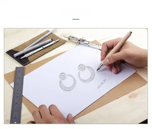 Macro view of geometric moon-shaped earring sketch with intricate diamond settings on paper