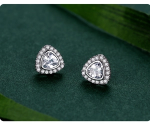 Macro view of triangle halo stud earrings featuring clear stones in silver setting