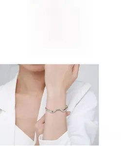 Detailed view of s925 silver wavy bracelet with micro-pave zircons on model's wrist