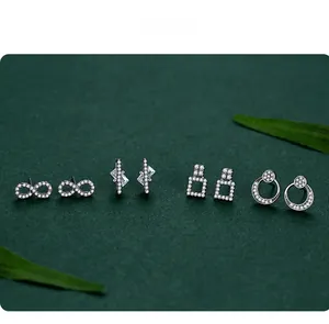 Macro shot of 925 silver stud earrings set with white zircons on a dark green leaf