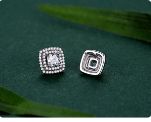 Detailed view of square halo silver earrings with cubic zirconia on a green background