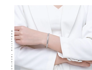 Dettaglio di un bracciale rigido argento con motivi geometrici su modella in bianco