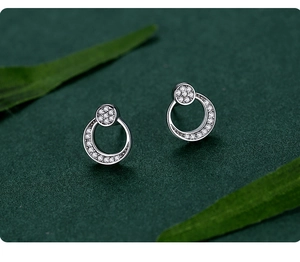 Detail of silver moon stud earrings with pavé cubic zirconia on green leaf background