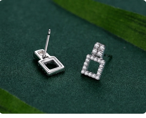 Macro shot of S925 sterling silver square earrings with inlaid zircon on green background