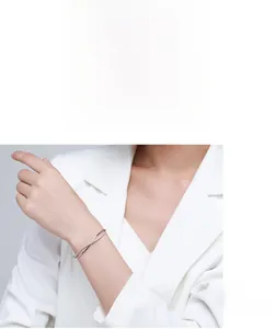 Polished silver bangle with crisscross zircon design worn on a female wrist