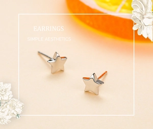 Boucles d'oreilles étoiles en argent S925 poli sur un fond décoratif chaleureux