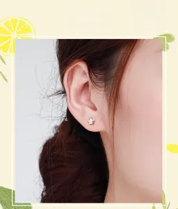 Gros plan de boucles d'oreilles étoiles minimalistes en argent S925 portées par un mannequin