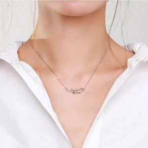 Elegant 925 sterling silver bow necklace with micro-pave crystals on a white shirt model