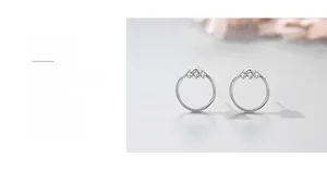 Close-up of minimalist silver geometric hoop earrings with triple micro-inlaid zircons