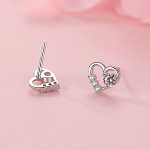 S925 sterling silver heart stud earrings with sparkling cubic zirconia on pink background