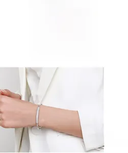 Detail of s925 silver bamboo bangle with pavé diamonds worn with a white blazer
