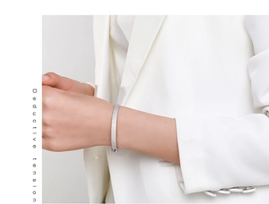 Close-up of a luxury S925 silver pave diamond bangle on a model wearing white suit