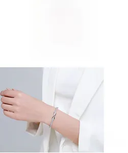 Detail of s925 silver infinity bow bracelet with zircon stones on a female wrist