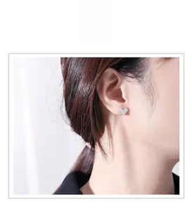 Gros plan de boucles d'oreilles cœur en argent S925 serties de diamants sur l'oreille