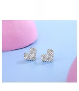 Détail macro de clous d'oreilles cœur pixel en argent S925 sertis de zircons cubiques blancs