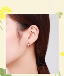 Close-up of polished silver C-shaped hoop earrings on female model's ear