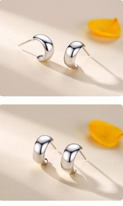 Close-up of minimalist wide C-shaped sterling silver stud earrings with high-polish finish