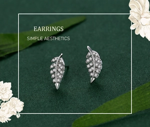 Detailed view of S925 silver leaf earrings with zircon pavé on a green background
