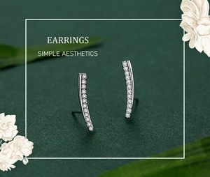 Detailed shot of curved S925 silver earrings with sparkling zircons on green surface