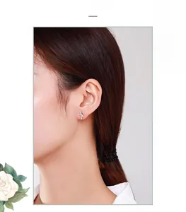 Close-up of S925 sterling silver geometric stud earrings worn by a model in soft lighting