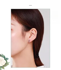 Detail view of S925 silver triangle stud earrings with zircons on earlobe