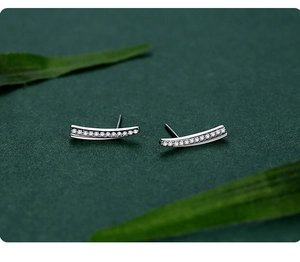 Macro shot of curved S925 silver stud earrings with sparkling pavé cubic zirconia
