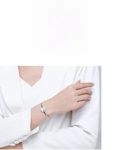 Detail of s925 silver open bangle with a circular pavé diamond setting on a female wrist
