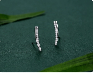 Macro shot of minimalist s925 silver curved earrings with pavé set zircon stones
