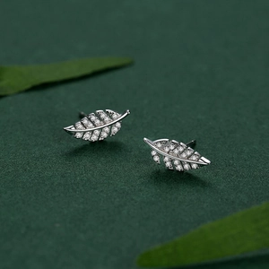 Elegant S925 silver feather earrings with zircon stones on natural leaf background