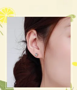 Close-up of minimalist s925 sterling silver ball stud earring on model's ear