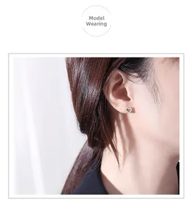 Close-up of heart-shaped S925 silver stud earrings with pavé zircons worn by a model