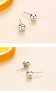Macro shot of minimalist silver bubble stud earrings with polished sphere on lemon background