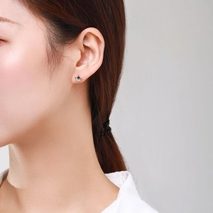 Elegant S925 silver crown stud earrings with black stones shown on a model's ear