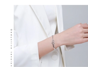 Detailed view of silver heart bracelet with pavé diamonds on a model's wrist
