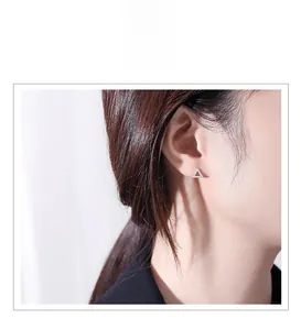 Macro shot of a sparkling silver triangle stud earring worn on a model's earlobe