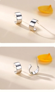 Detailed views of minimalist silver-polished C-shaped stud earrings on beige background