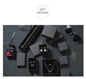 Vue à plat d'un coffret cadeau noir avec bagues feuilles d'argent et collier