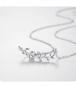 Macro shot of silver leaf pendant with three clear zircons on a fine cable chain