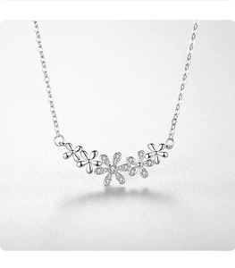 Macro detail of S925 silver necklace with five daisy flower pendants and zircons