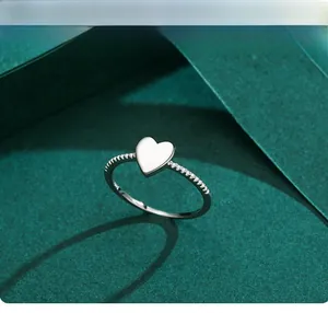 Macro detail of S925 sterling silver heart ring with pave set stones on a textured background