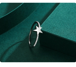 Détail de la bague étoile en argent s925 avec zircons scintillants sur fond vert chic