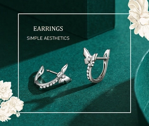 Macro detail of silver bow earrings with zircon pavé setting on green gift box