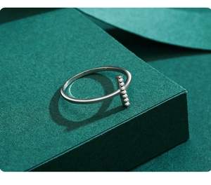 Detail of minimalist S925 sterling silver ring with inlaid white zircons on a textured base